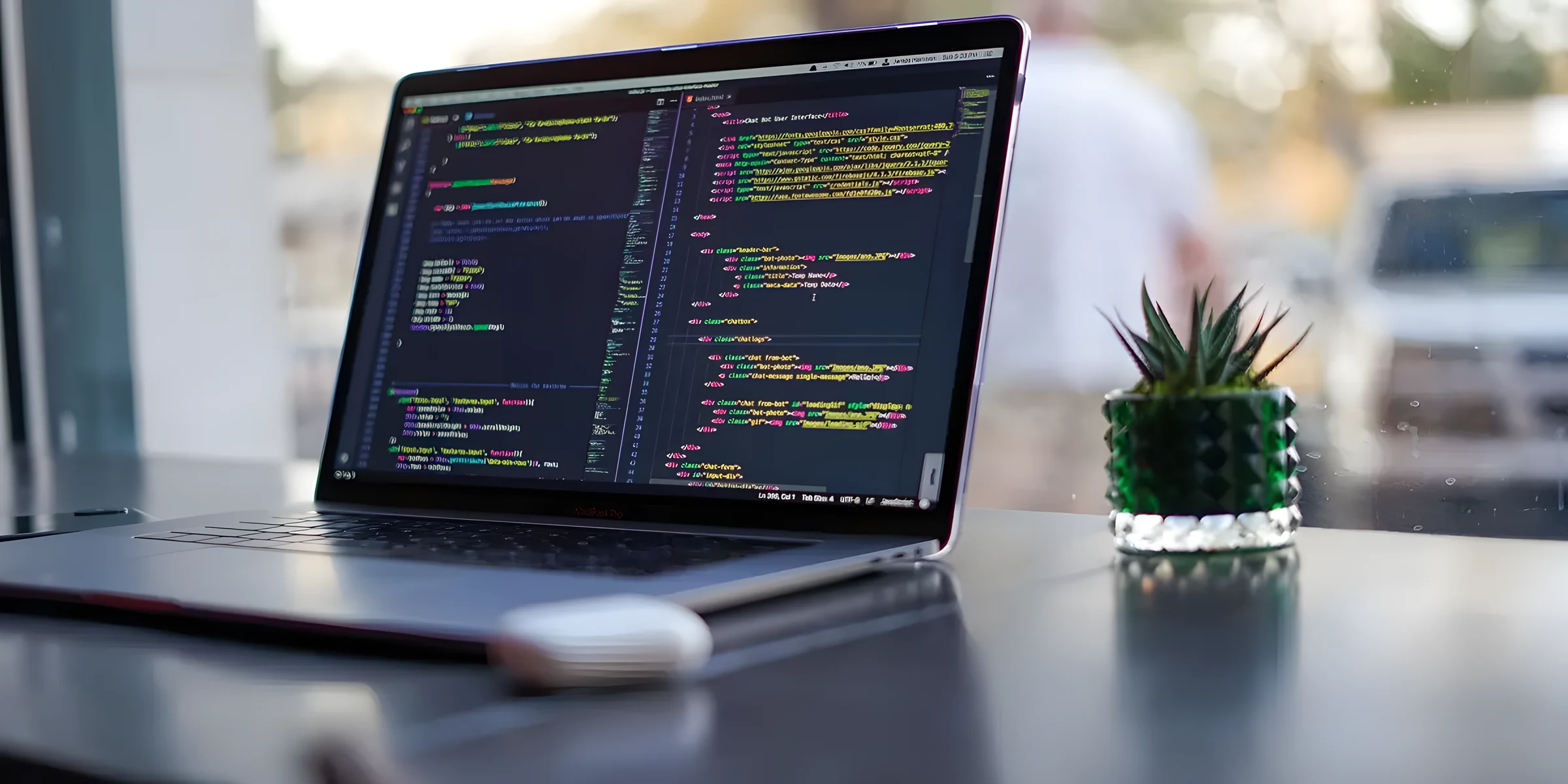 Laptop with source code open in the editor, on a desk next to a window