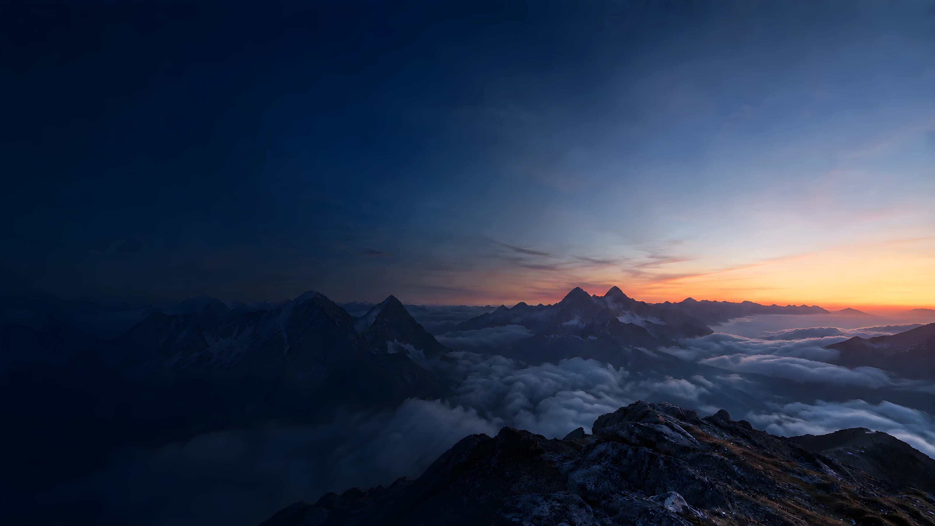 A lone hiker overlooking alpine mountains and clouds at sunrise